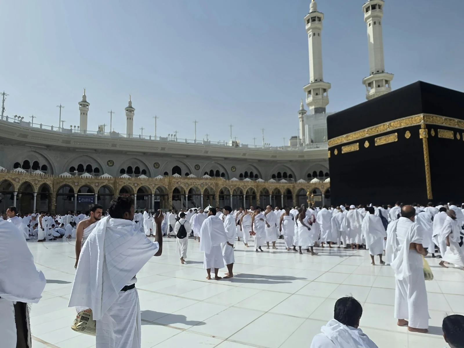 Best Umrah Packages In UK — A cheerful group of UK pilgrims gathers in a modern Makkah hotel lobby, luggage Best Umrah Packages In UK — A cheerful group of UK pilgrims gathers in a modern Makkah hotel lobby, luggage